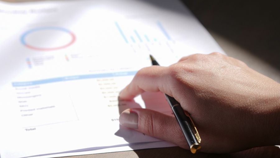 hand holding pen on financial papers
